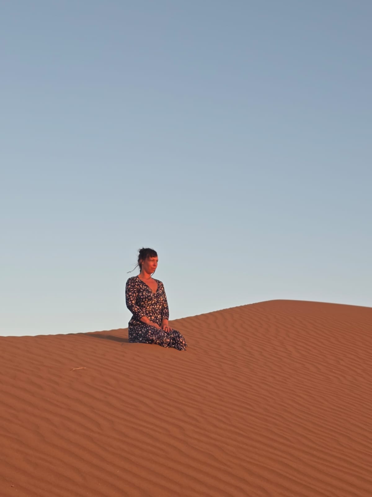 Dana sitting in stillness and presence in the vastness of the desert