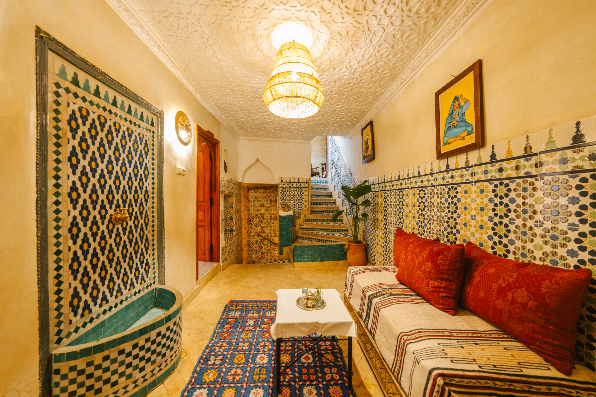 A shared room with mosaics and red cushions